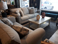 A living room with two Superstyle beige 9613 loveseats, a wooden coffee table, and a car visible outside the window.