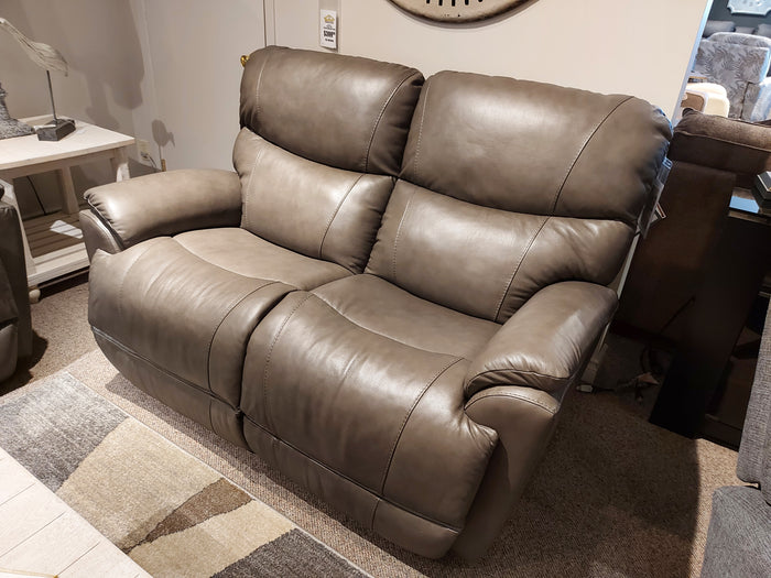 The 724 Trouper Leather Reclining Loveseat by La-Z-Boy delivers reclining comfort in a cozy room, complemented by soft lighting and split back cushions, all beautifully arranged on a patterned area rug.