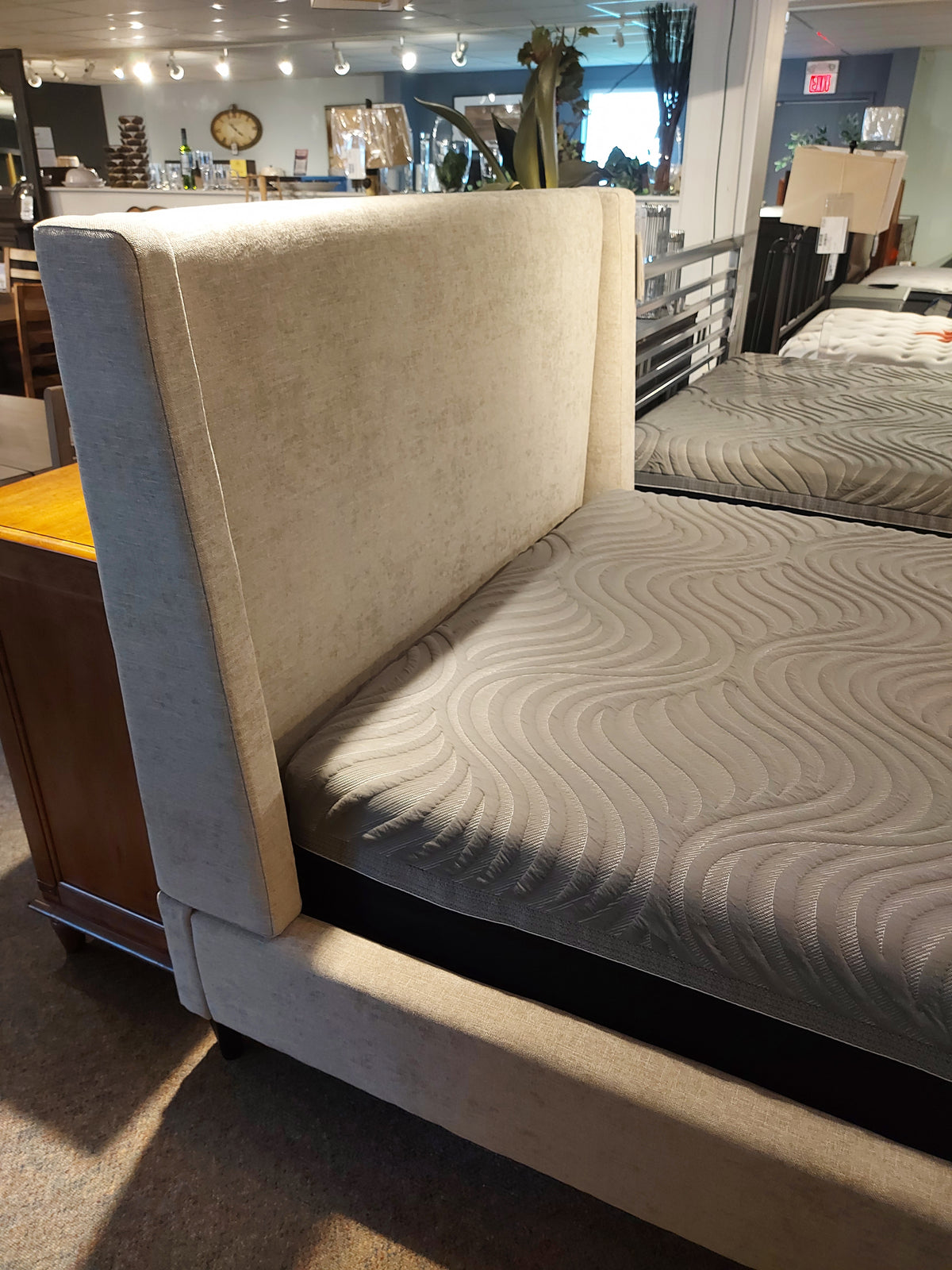 The 77132 Skye Queen Upholstered Bed by Palliser features a wingback headboard, now displayed in a showroom.