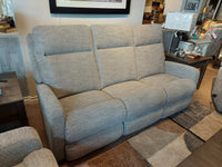 The La-Z-Boy 747 Finley Power Reclining Sofa, featuring a contemporary gray upholstery with three seats, is showcased in a furniture store showroom alongside decorative items.