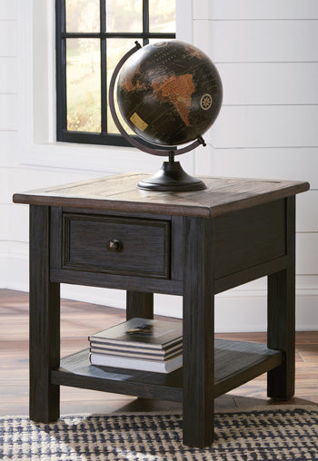 The Ashley T736 Tyler Creek End Table, with its drawer and textured black finish, holds a globe and books by the window.