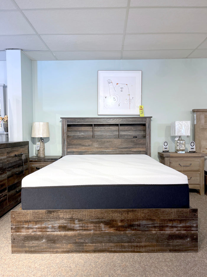 Create a stylish rustic industrial bedroom setup with the Ashley B211 Drystan Queen Bookcase Bed featuring convenient storage drawers, a comfortable mattress, two elegant nightstands complete with lamps, and striking wall art to complete the room.