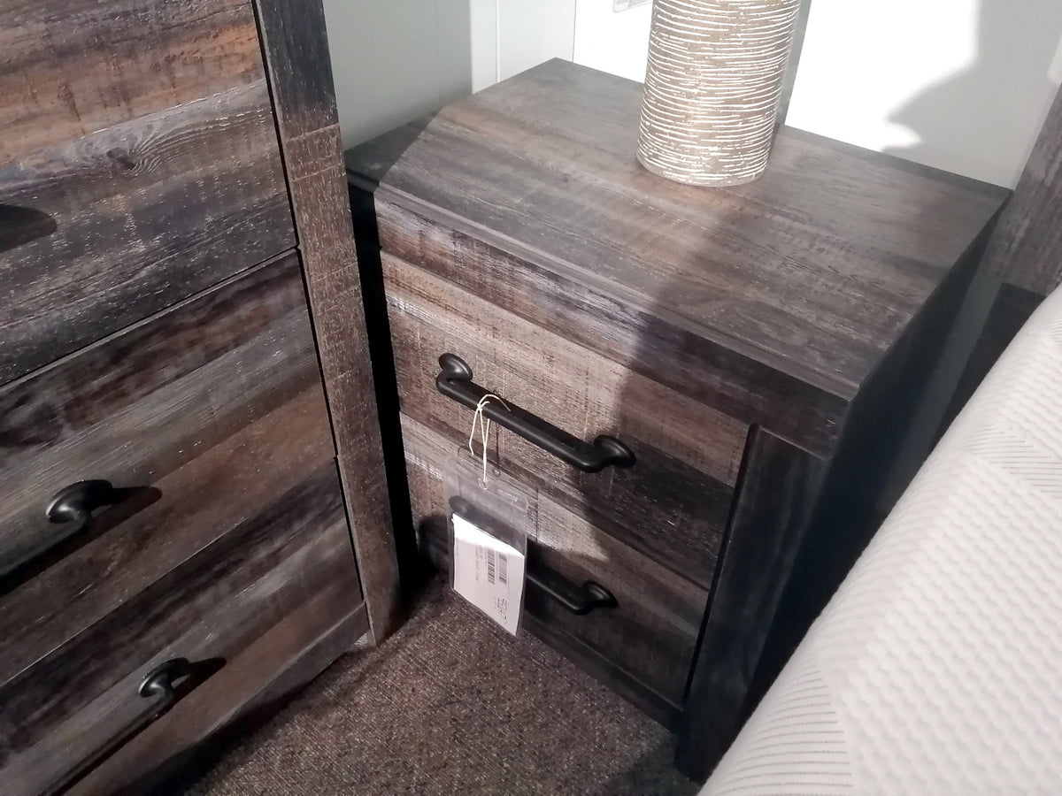 The B211 Drystan Night Stand by Ashley, with two drawers and black handles, complements matching furniture perfectly.