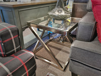 The Coylin Square End Table by Ashley, with its glass top and metal frame, sits between a gray sofa and a plaid chair.