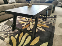 Ashley T351 Noorbrook Table Set on a floral rug in the living room, echoing a farmhouse style with sofas in the background.