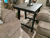 The T351 Noorbrook Table Set by Ashley sits amid beige chairs, with visible cords tucked beneath.