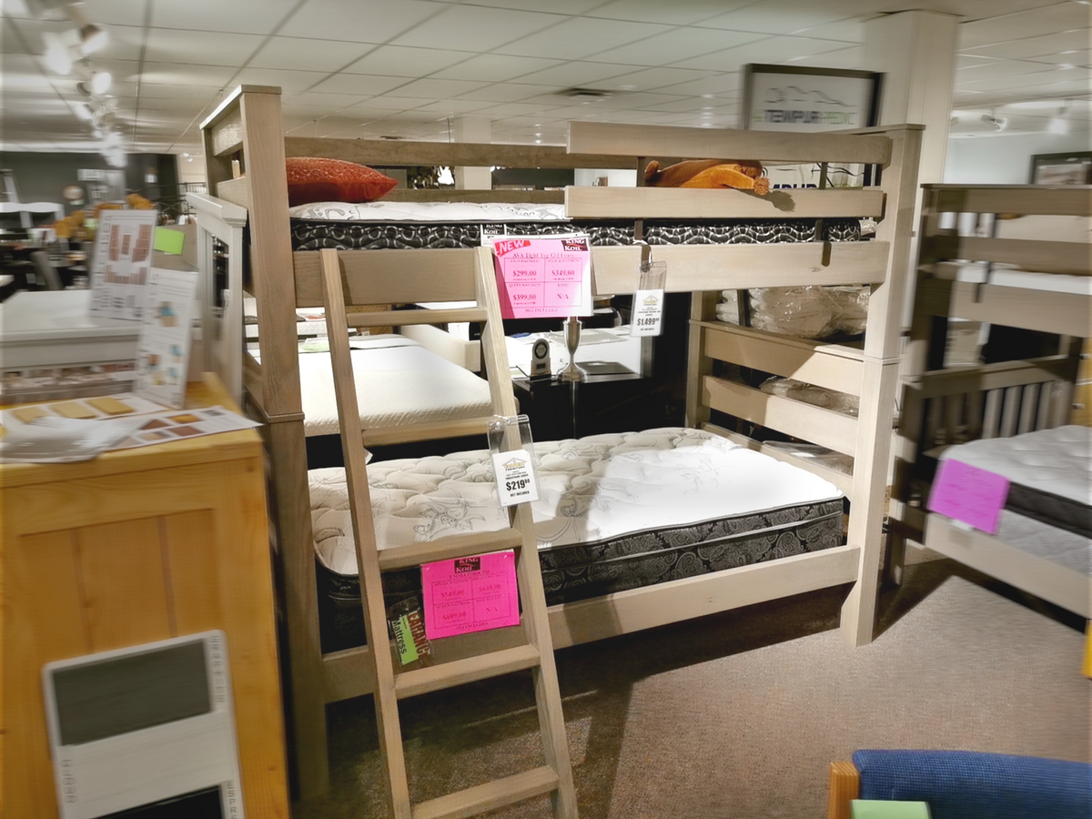 A Crate S43905 Twin Bunkbed made from Southern Yellow Pine and featuring a robust TimberFrame is elegantly showcased in a furniture store, accompanied by tags and price labels.