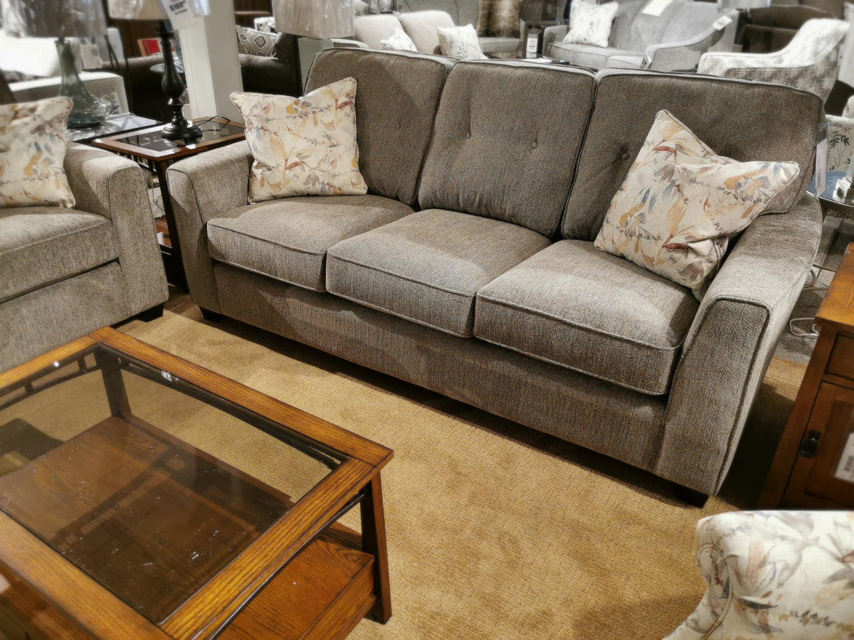 This contemporary style 2967 Sofa by Decor-rest, available in customizable brown fabric, comes with two patterned pillows. It is complemented by a matching armchair and sits beside a wooden coffee table on a beige carpet.