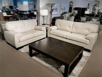 Two St. Lawrence Leather Sofas by Leather Craft face a large dark wood coffee table on a geometric rug in a showroom.