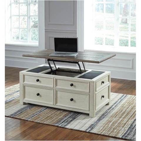 Ashley Bolanburg Lift-top Cocktail Table set on a striped rug in a room with large windows.