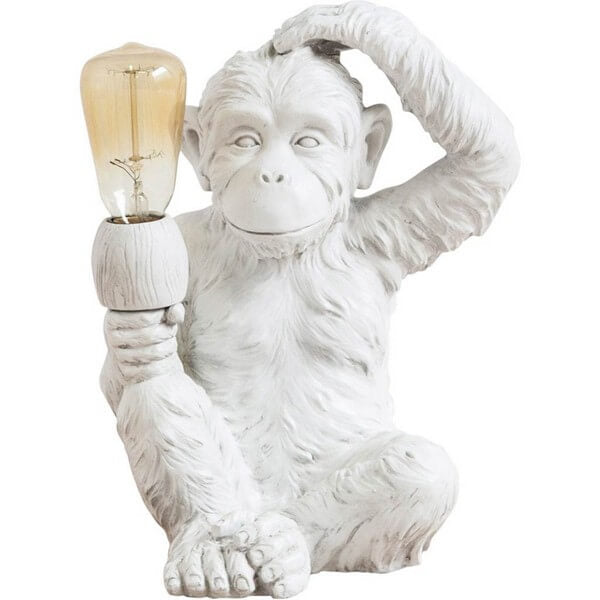 The Mercana 65319 Simia Table Lamp features a monkey-shaped design with one hand holding a bulb and the other thoughtfully resting on its head, capturing the whimsical charm of a pondering monkey statue.