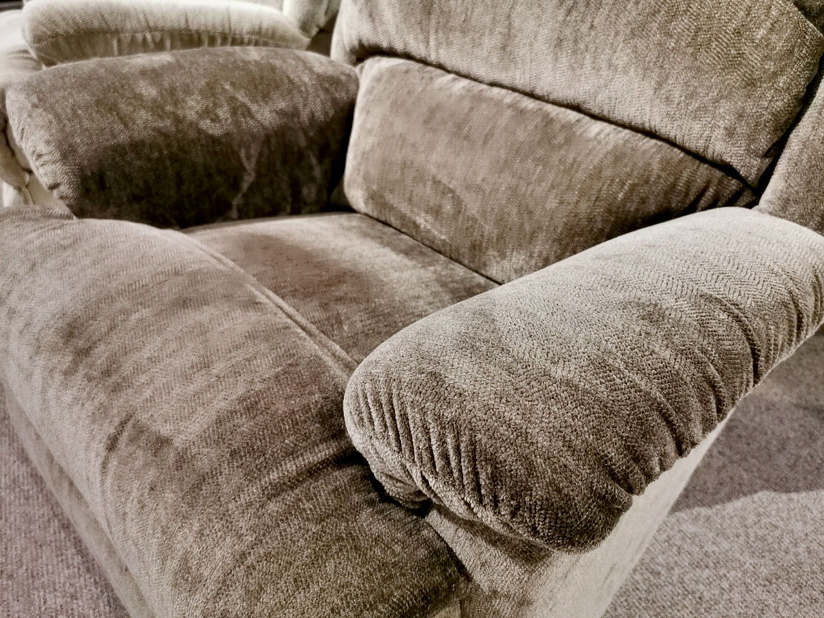 Close-up of a plush, beige upholstered 519 Astor Rocker Recliner by La-Z-Boy, featuring soft cushioning and textured fabric, in a well-lit room.