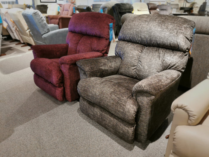 Displayed in a showroom are two ultra-plush La-z-boy Reed Rocker Recliners, one in burgundy and one in gray, offering a seamless zone of comfort with their upholstery.