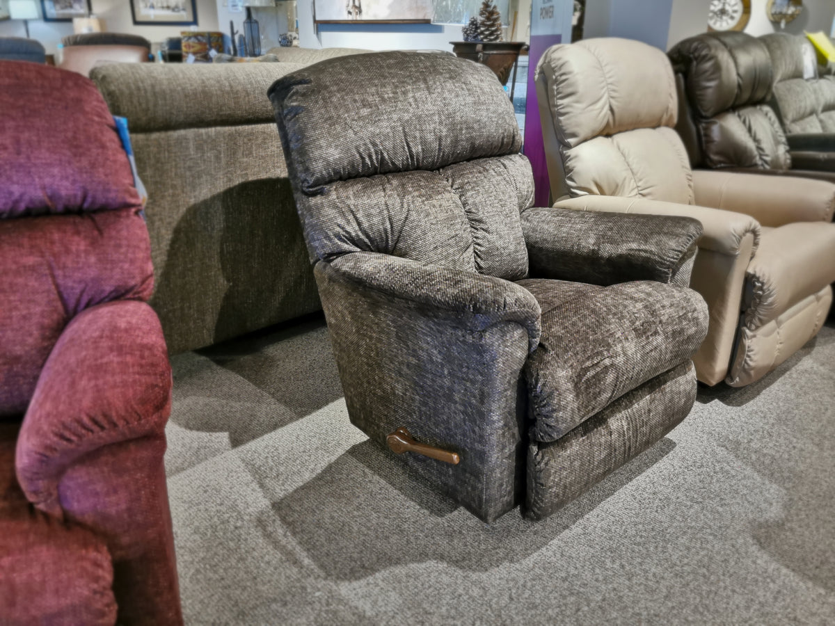 A row of ultra-plush casual recliners in various colors adorns the showroom floor, each promising a continuous zone of comfort. Among them, the La-Z-Boy 704 Reed Rocker Recliner stands out with its sleek design and soothing motion.