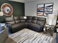 The living room showcases a La-Z-Boy 724 Trouper Reclining Corner Sectional in dark gray, complemented by two abstract paintings, a round mirror, a lamp on a side table, and a striped rug.