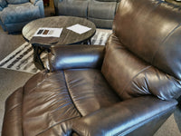 The La-Z-Boy 724 Trouper Leather Rocker Recliner, in luxurious brown leather, is positioned next to a round table with papers, providing excellent lumbar support for relaxation in the living room.