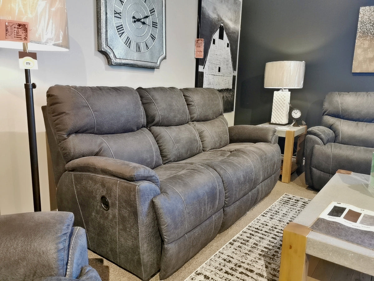 A 724 Trouper Reclining Sofa by La-z-boy in gray adds elegance to a modern living room, which is beautifully decorated with artwork, a wall clock, and a matching armchair with chaise legrest.