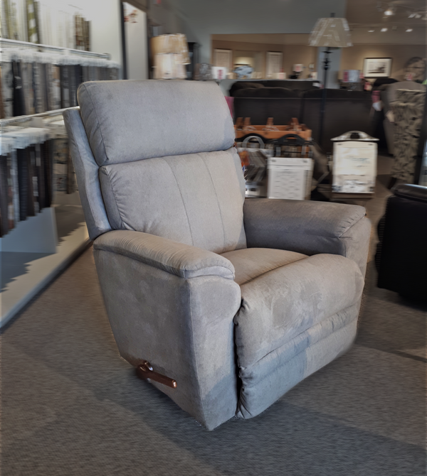 The La-z-boy 754 Talladega Rocker Recliner is showcased in a furniture store showroom, surrounded by various decor items. It offers modern comfort with its sleek design and convenient USB port.