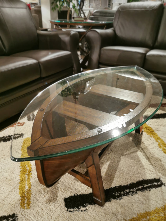 Magnussen's T2214 Beaufort Boat cocktail table between brown leather couches on a patterned carpet.