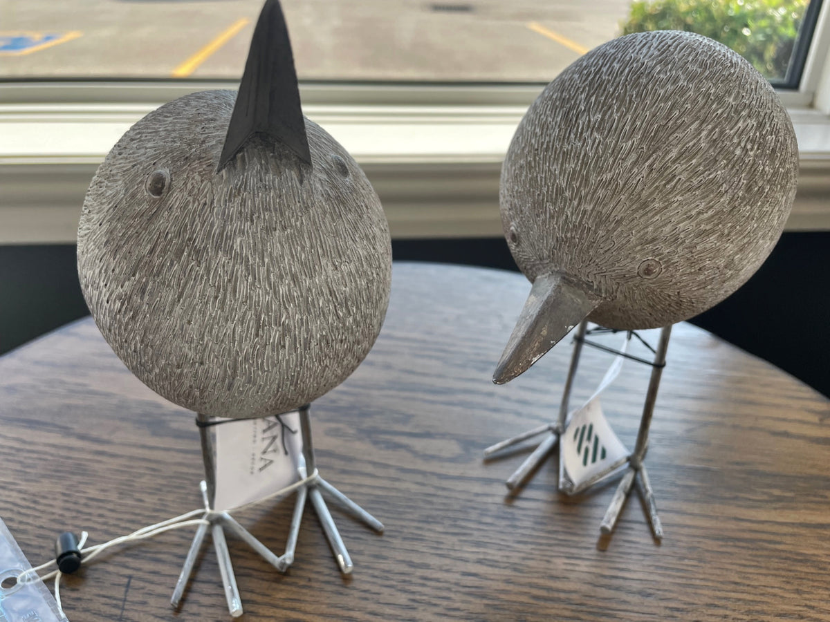 Two Mercana 68079 Snipe Bird Ornaments adorn a wooden table near a window, enhancing the décor style.