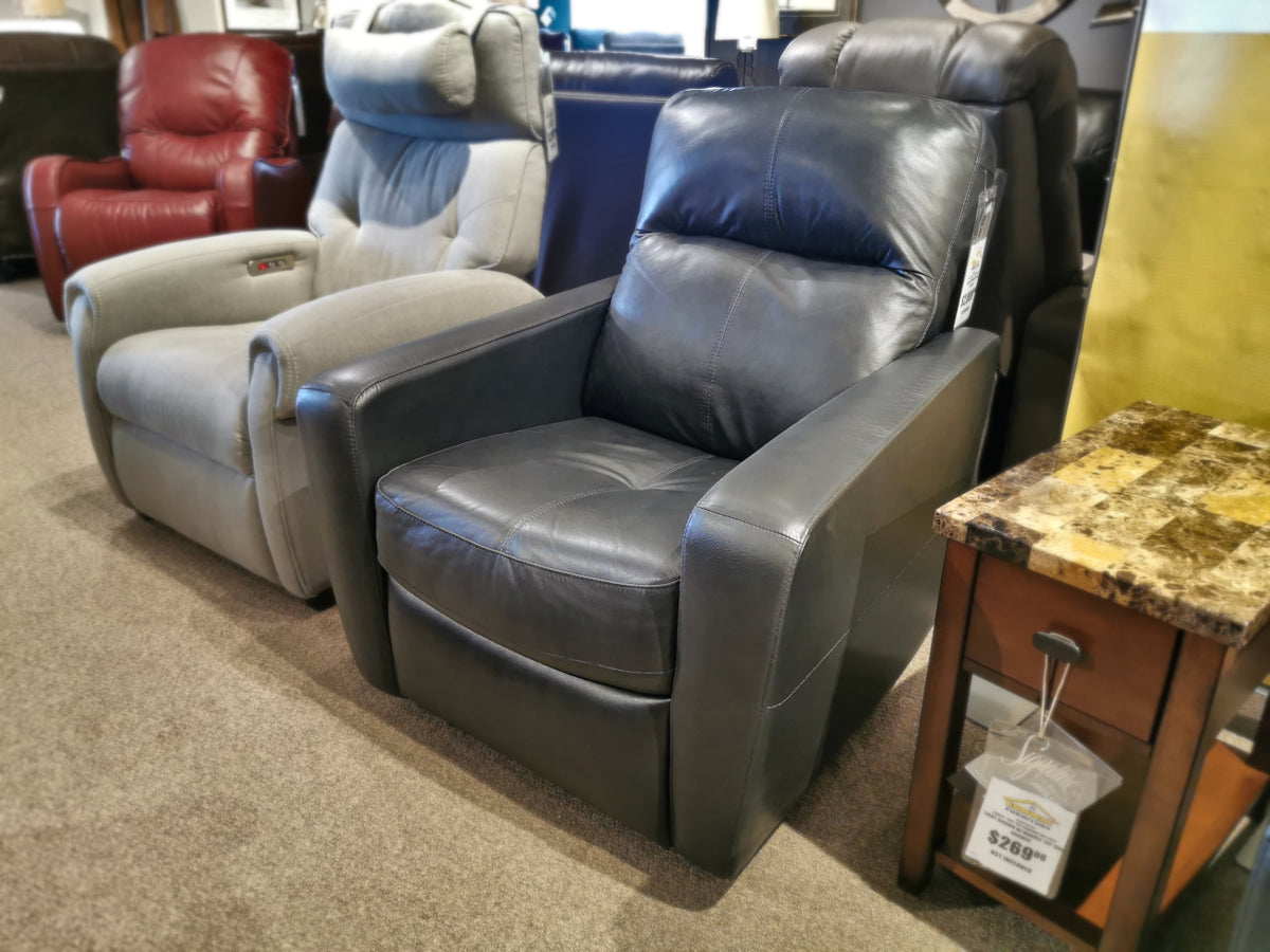 A row of Palliser's 40132 Cairo Power Wall Recliner chairs in a furniture store, showcasing designs in anthracite leather with an elegant flared track arm, complemented by a wooden side table.