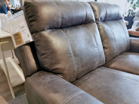 The Palliser 41121 Westpoint Loveseat, upholstered in grey leather, is on display with an attached price tag, highlighting its classic comfort and extra-wide seating.