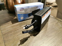 A black battery charger with two attached cables rests on a table, accompanied by a boxed product labeled "49001 Battery Pack - PALLISER" in the background. Perfect for your Palliser power reclining furniture or Conway power recliners, this rechargeable battery pack ensures seamless convenience.