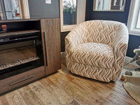 The Palliser 77090M Dorset Swivel Chair with throw pillows is near a wooden cabinet on wood floors by a window.