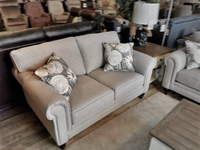 Superstyle's 9613 Loveseat: gray with premium foam seating and floral-patterned pillows, showcased in a showroom.