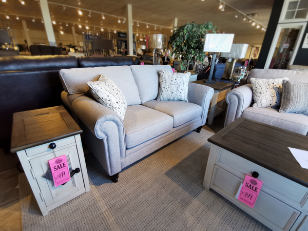 Living room display: Superstyle 9613 gray loveseat with premium foam, decorative pillows, and hardwood side table in-store.