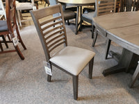 The Annapolis Side Chairs by Winners Only, featuring a cushioned seat and a dark chocolate finish, are on display in a furniture store, surrounded by dining tables and other chairs.