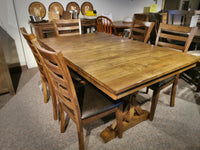 Newport Dining Set by Winners Only, featuring a distressed finish, displayed in a showroom, includes a wooden dining table with eight matching chairs.