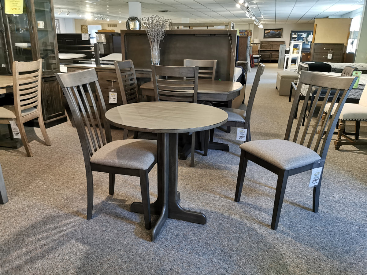 Explore the DF30RD Delfini Dining Table Package by Winners Only in the showroom, which includes a round table and four chairs made from solid hardwood. Its transitional design perfectly complements contemporary aesthetics, providing elegance and durability for any modern home.